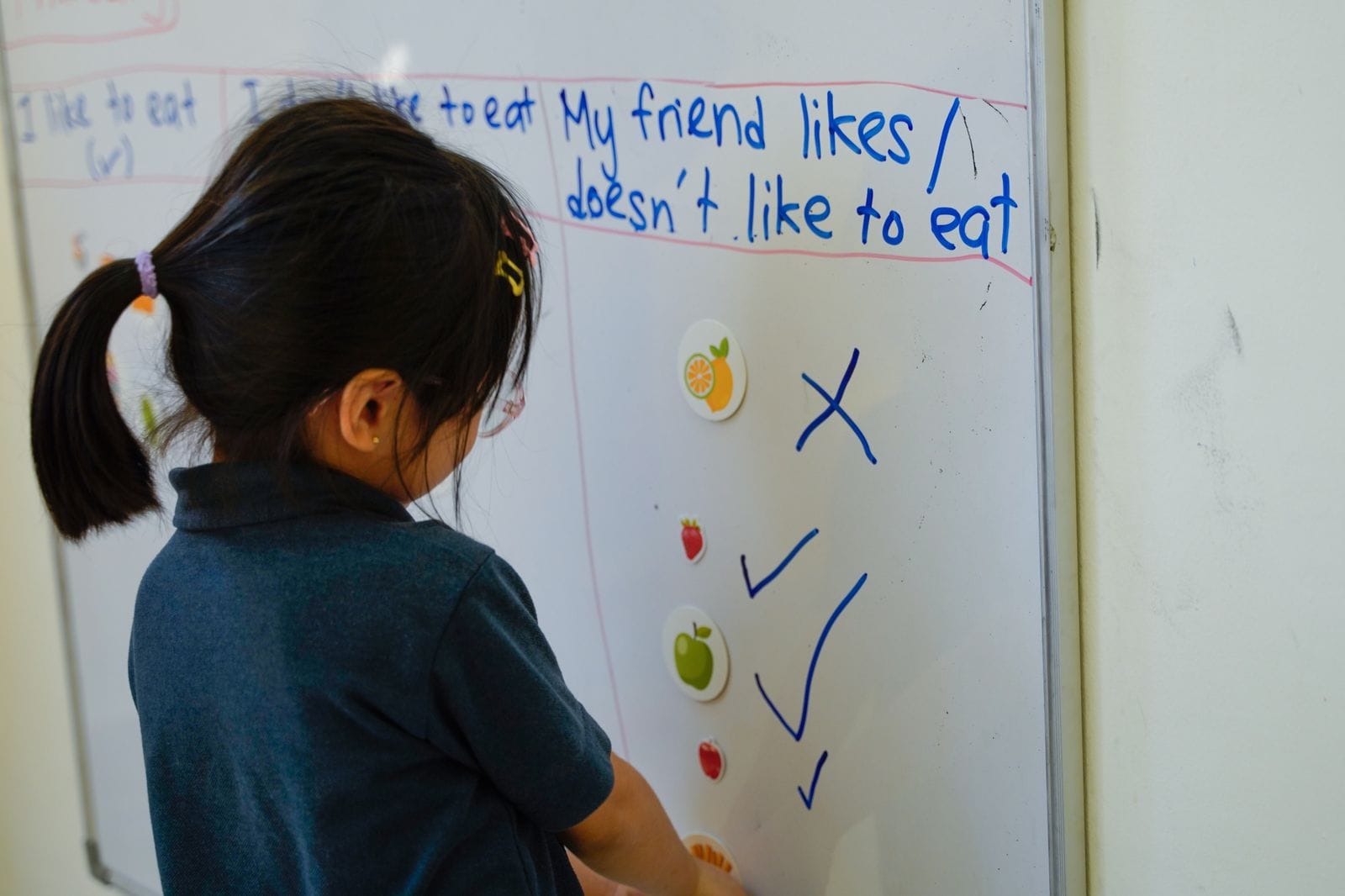 A child writing English sentences on a whiteboard